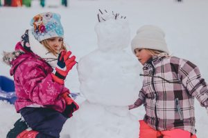 dzieci lepiące bałwana na śniegu